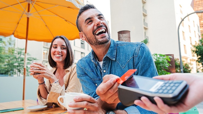 Person smiling, paying for coffee