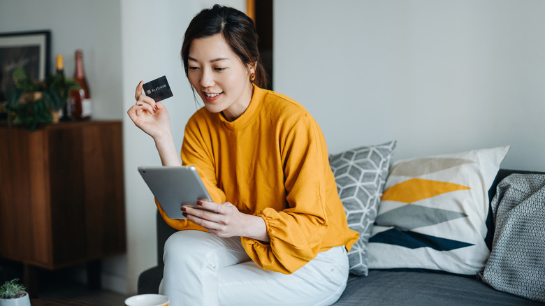 Woman reading something on tablet while holding credit card