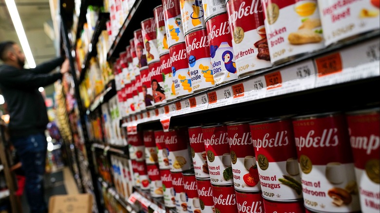 Person stocking shelves, Campbell's soups