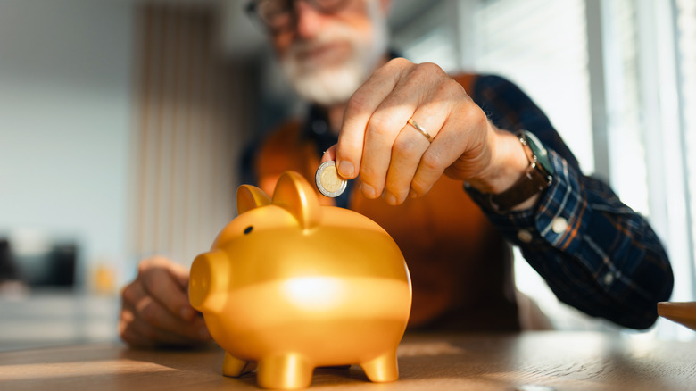 senior putting money in piggy bank