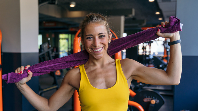 A woman smiling and holding a towel in a gym during a workout