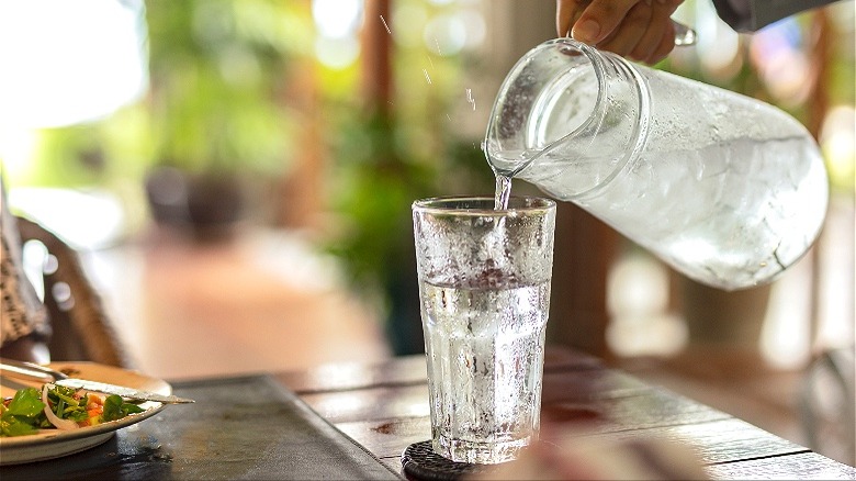 Waiter pouring water into glass