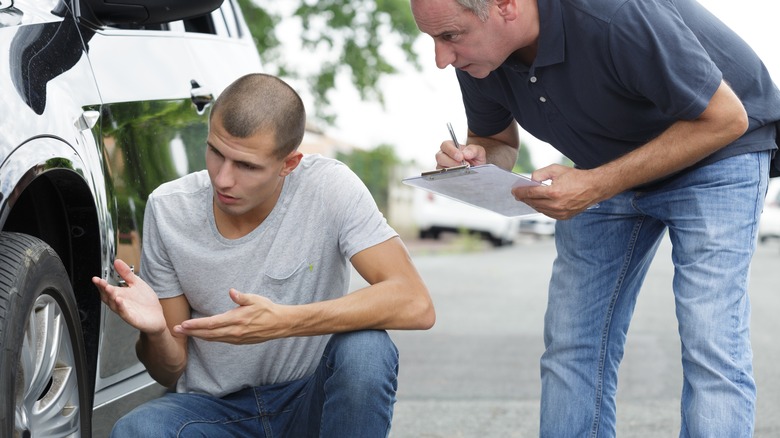 Two men looking at a car tire