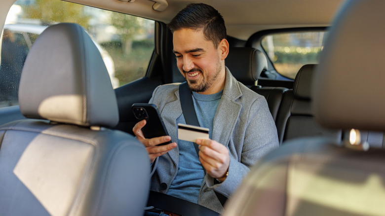 A smiling man holding a credit card and cellphone