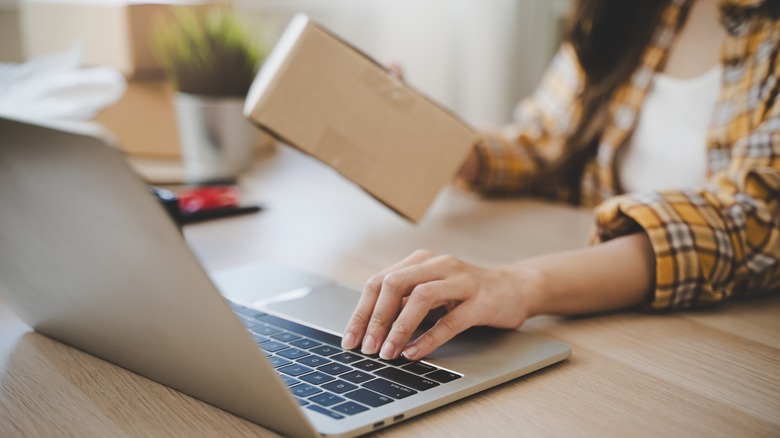 A woman holding a parcel while typing