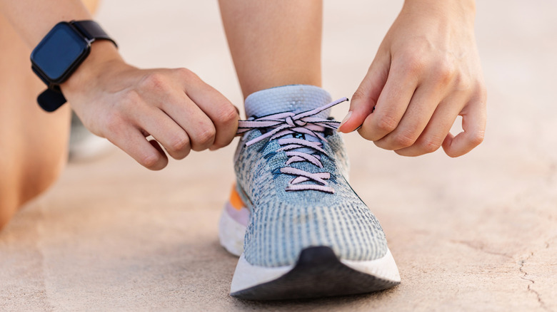 person tying the laces of a running shoe