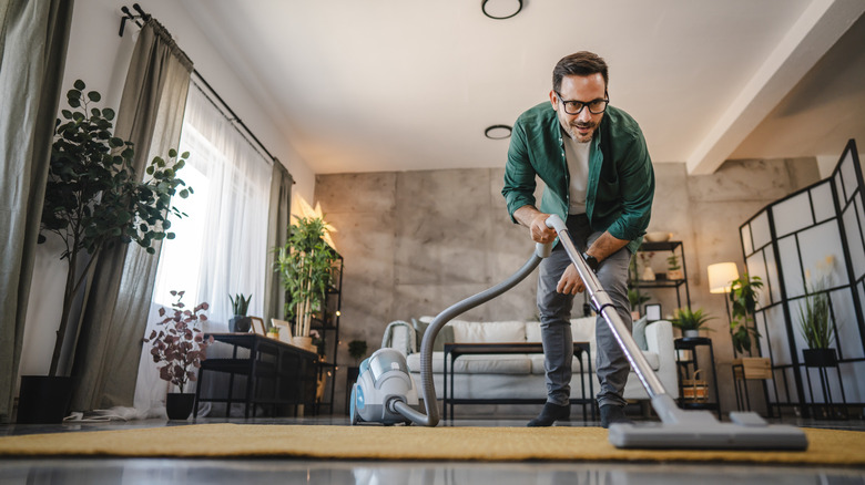 man vacuuming a rug