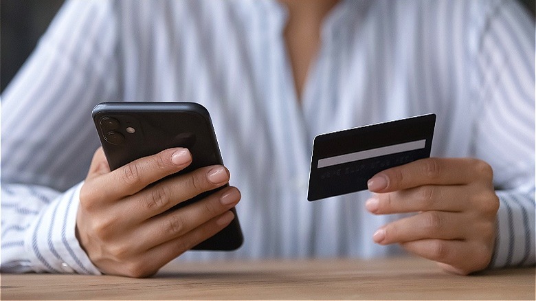 Person holding credit card, smartphone