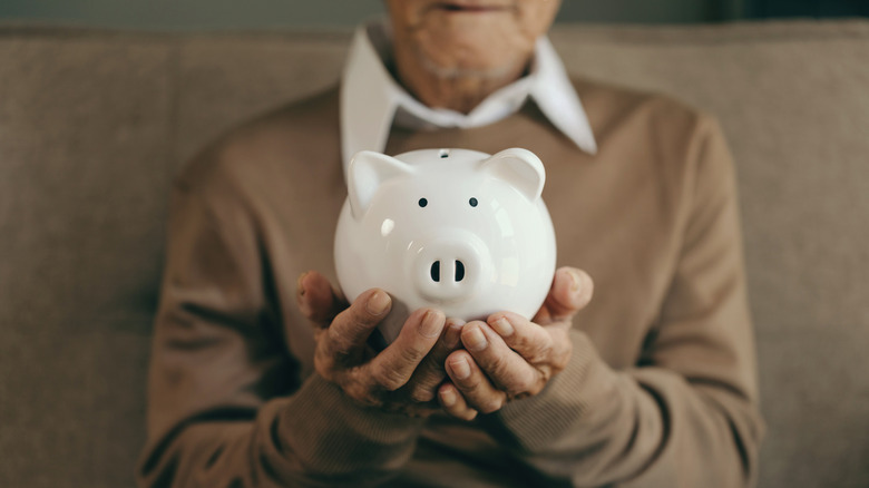 senior holding piggy bank