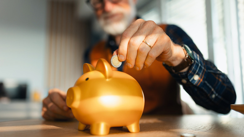 man putting money in piggy bank