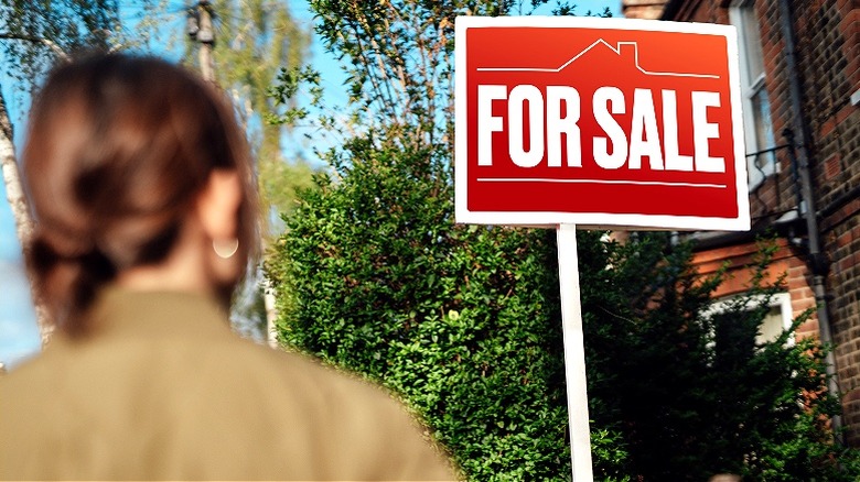 Person looking at "For Sale" sign