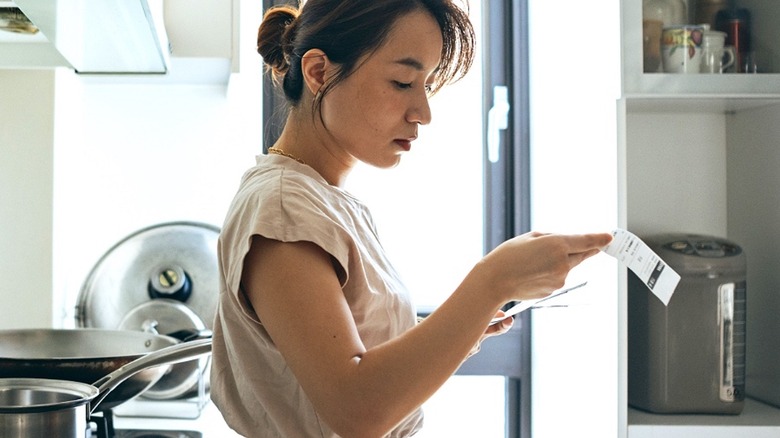 Person reviewing receipt in kitchen