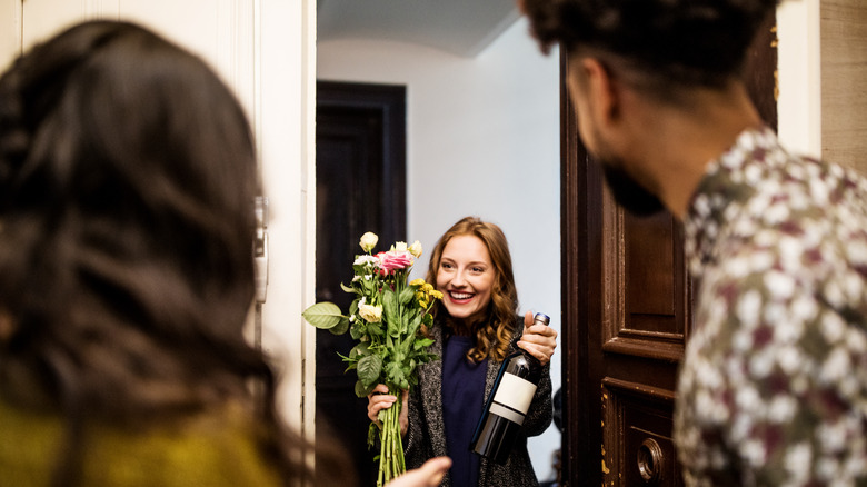 A smiling woman holding a bottle of wine