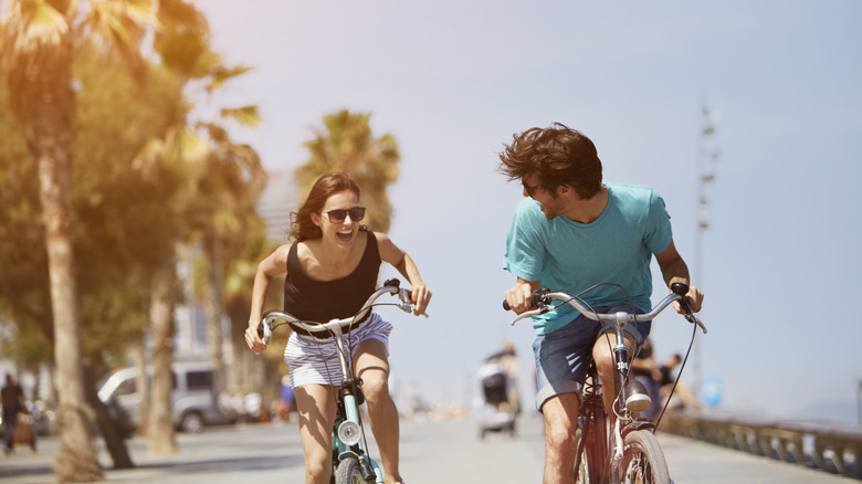A laughing couple riding their bikes down the street