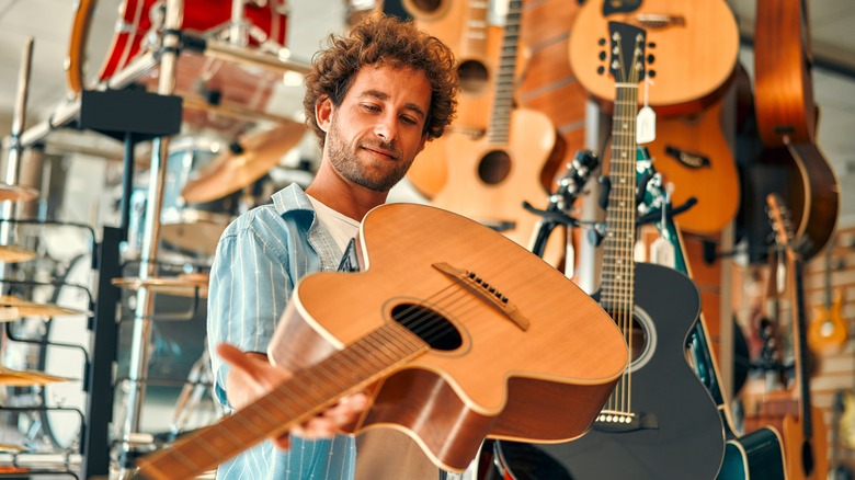 A man closely inspecting a guitar in a guitar shop