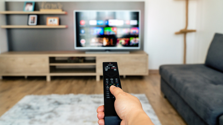 A hand pointing a TV remote at a TV