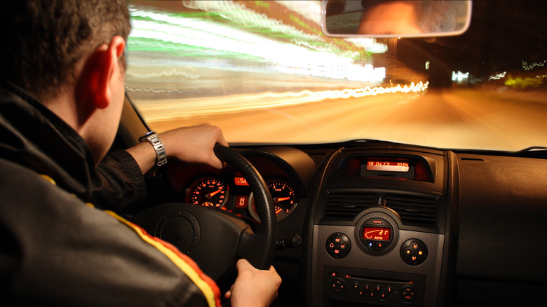 A man sitting behind the wheel of a speeding car