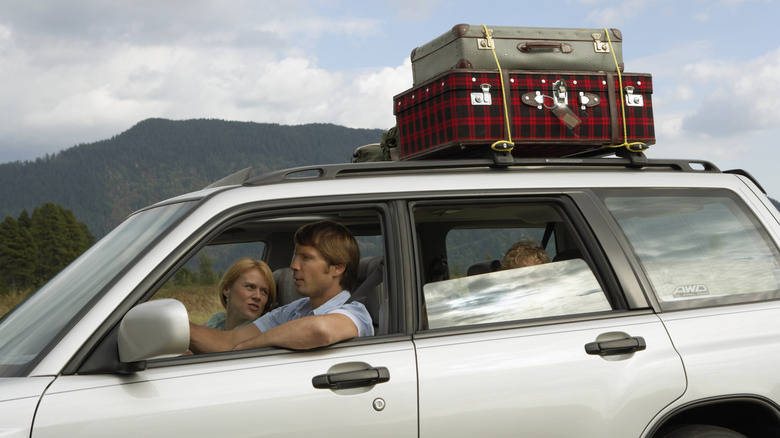 A family in a car with luggage on a roof rack