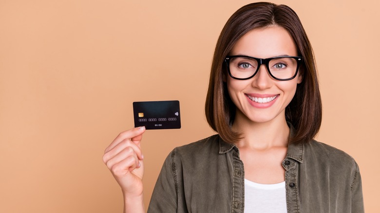 A smiling woman holding a credit card