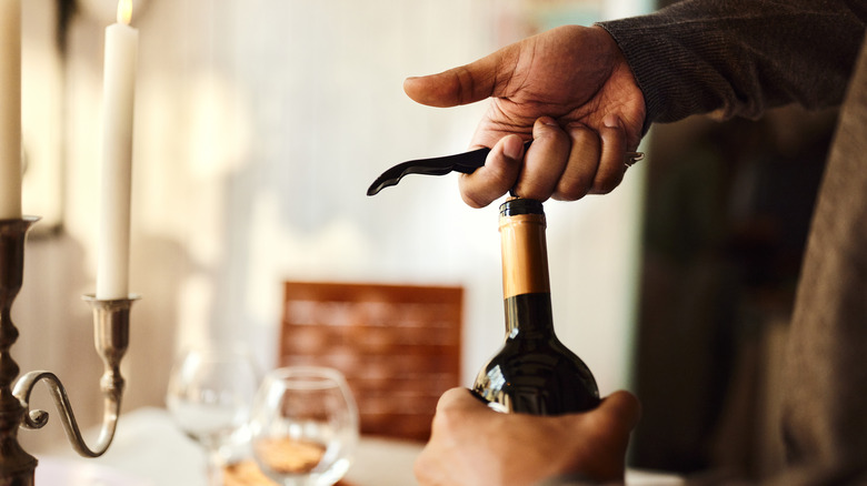 Hands uncorking a wine bottle