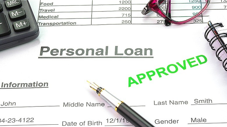 Personal loan paperwork with pen, glasses, calculator, and notebook forming a border