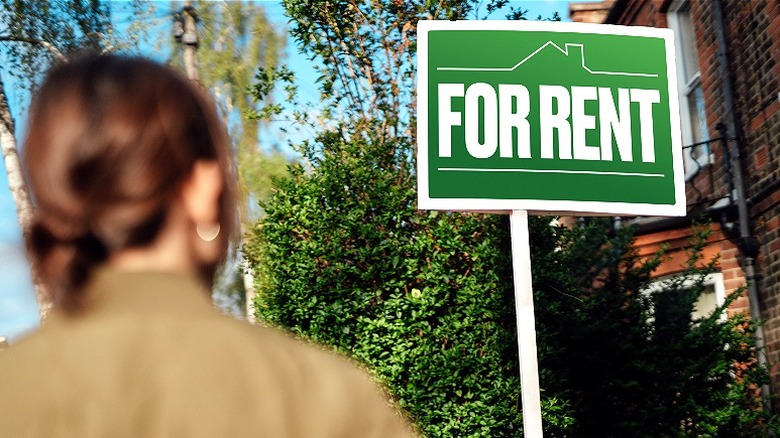 Person looking at "FOR RENT" sign