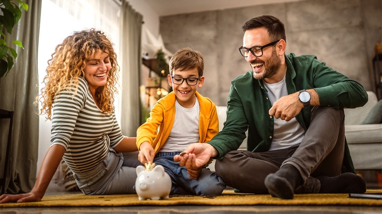 Laughing family filling piggy bank