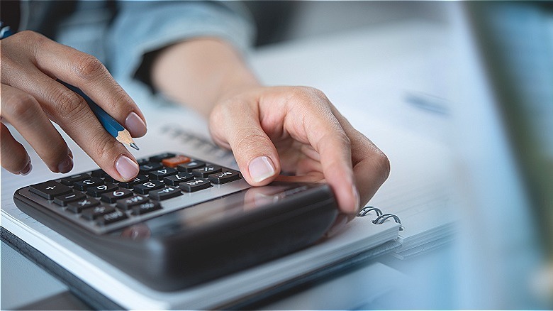 Hand holding pencil, using calcuator