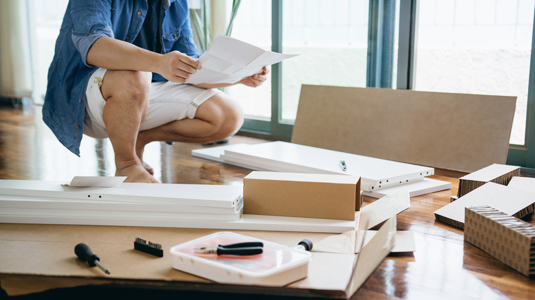 Man reading furniture assembly instructions