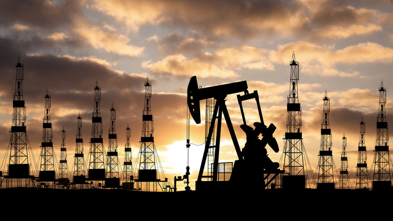 machinery at an oil field with setting sun in background