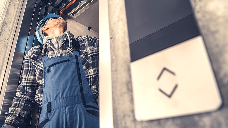 Elevator repair person inspecting elevator