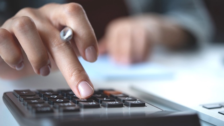 Hand making calculations holding pen