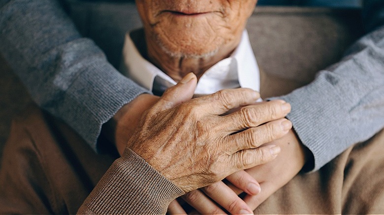 Older person embraced from behind