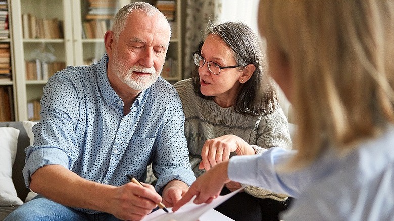 An elderly couple signing a document at home