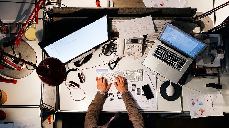 Above view at a person typing at their desk with two monitors