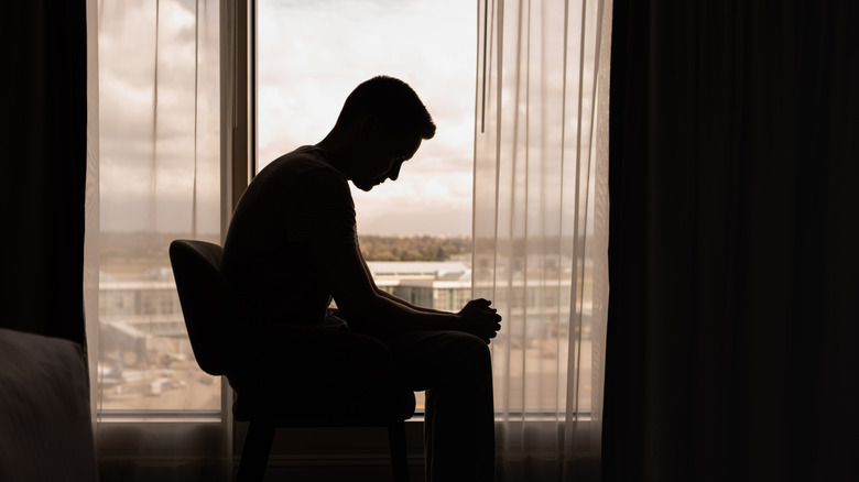 A man looking sad in a darkened room.