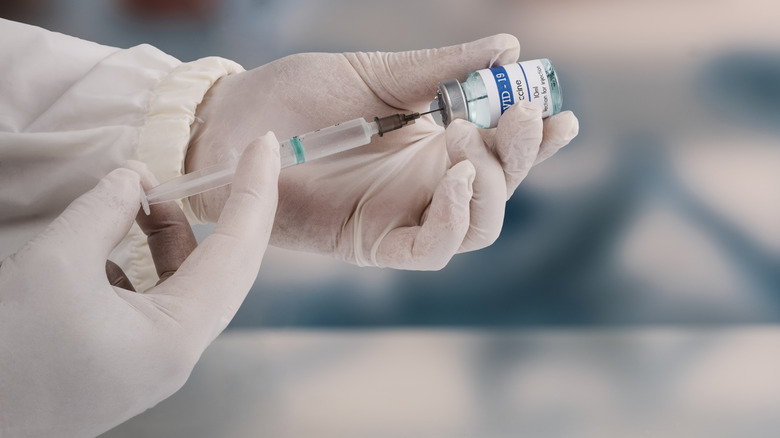 Person wearing gloves holding a COVID-19 vaccine vial