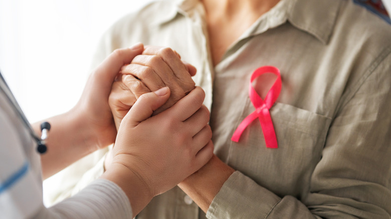 A breast cancer pink ribbon pinned to a woman's shirt