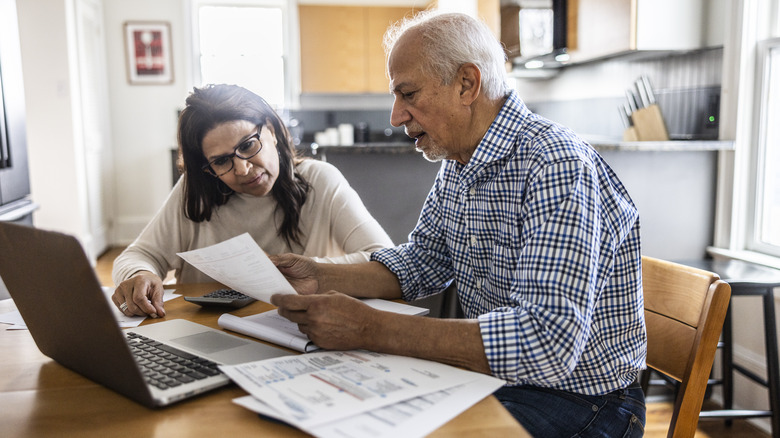 Senior couple paying bills at kitchen table