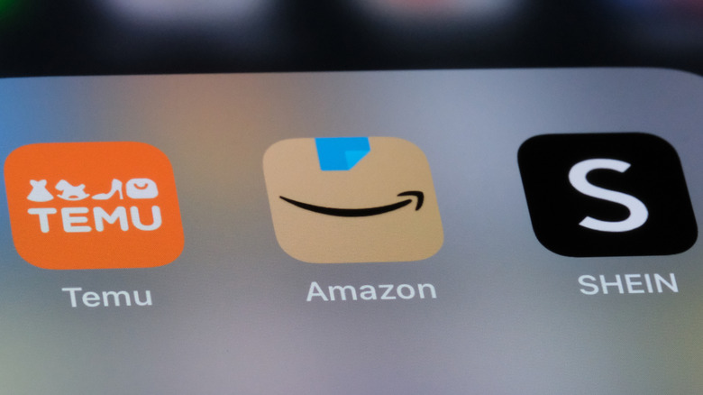 Close-up of a mobile phone bearing icons for Temu, Amazon, and Shein apps.