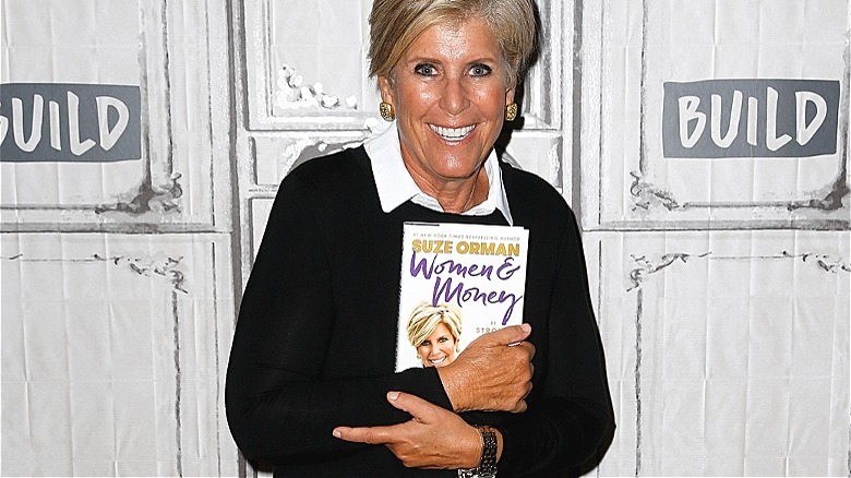 Suze Orman holds her book