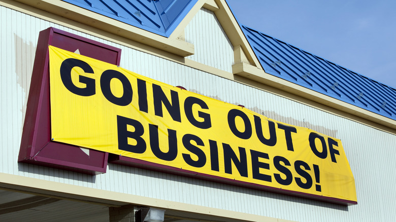 A going-out-of-business banner hangs over a store sign.