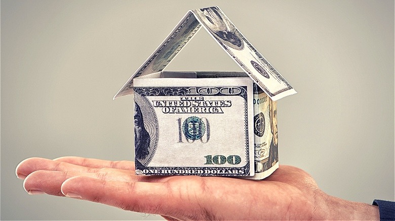 Currency origami house atop hand