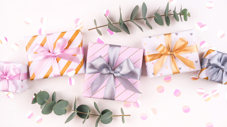 Pastel-wrapped wedding gifts splayed attractively across a table strewn with confetti and eucalyptus branches.