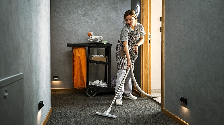 Person vacuuming rental room hallway