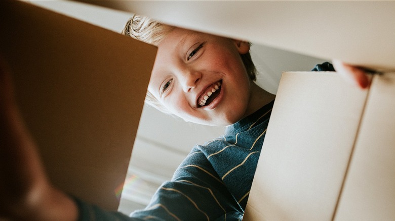 Retro smiling kid opens box to look inside