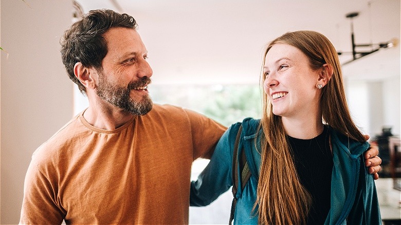 Father, daughter loosely embrace smiling