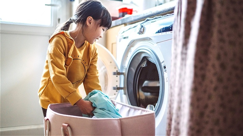 Child loads clothes washing machine