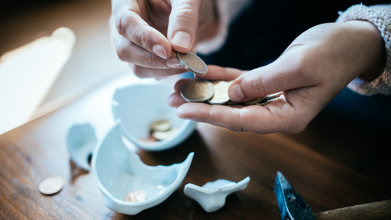 Hands counting coins from a broken piggy bank.