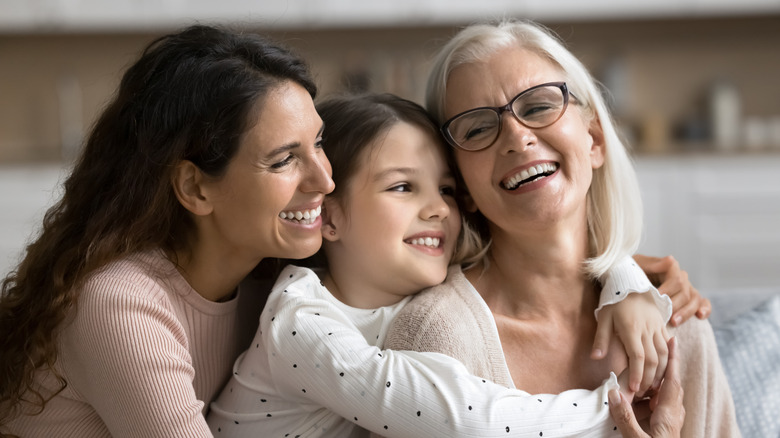 Three generational women embracing, smiling spending pleasant time together,